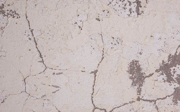 Close view of cracked and chipped plaster on a wall
